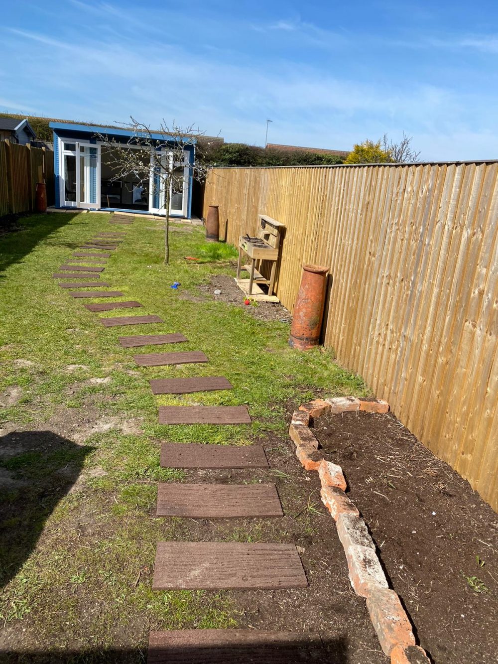 long narrow garden with centre path and garden room at end